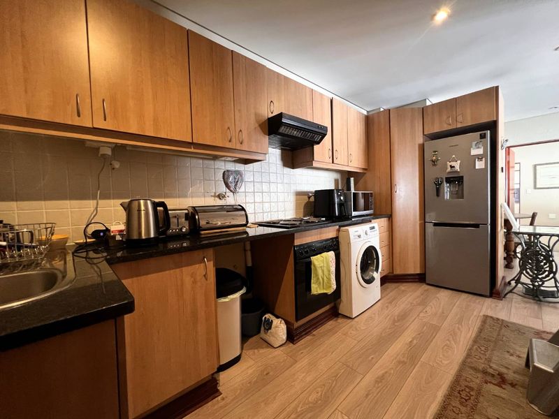 A functional kitchen featuring wood-look laminate cabinetry, granite countertops, tiled backsplash, and integrated space for a washing machine and oven.