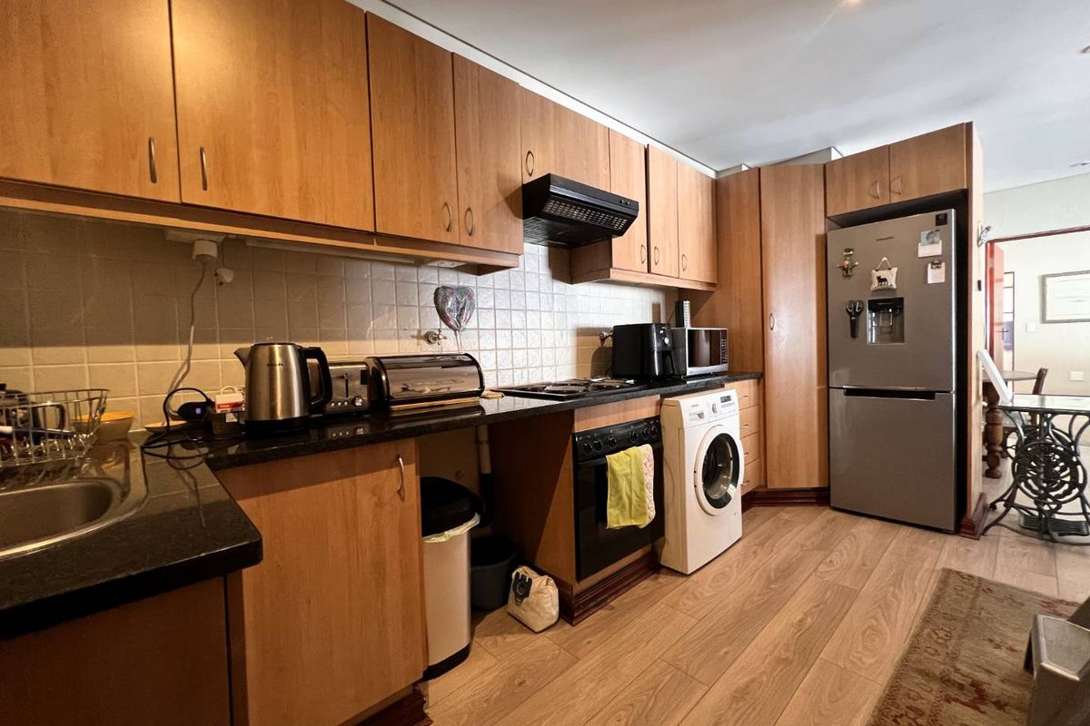 A functional kitchen featuring wood-look laminate cabinetry, granite countertops, tiled backsplash, and integrated space for a washing machine and oven.