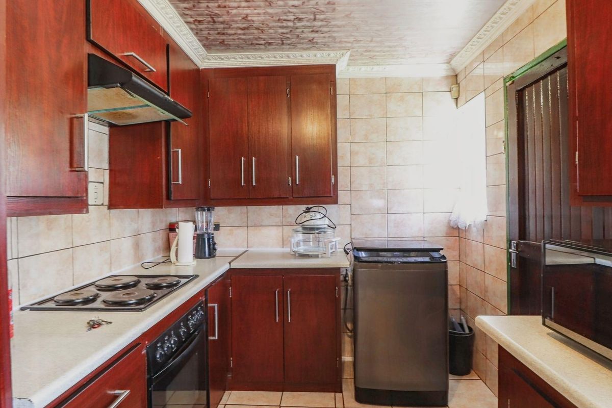 A functional kitchen featuring dark wood cabinetry, tiled walls, a built-in oven, and a hob with an extractor fan.