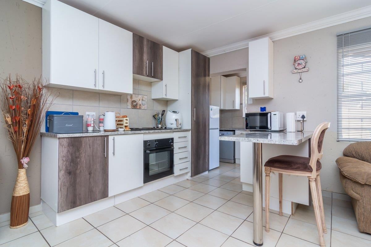 Functional kitchen featuring two-tone cabinetry, granite-look countertops, built-in oven, and a breakfast nook with a metal pedestal table.