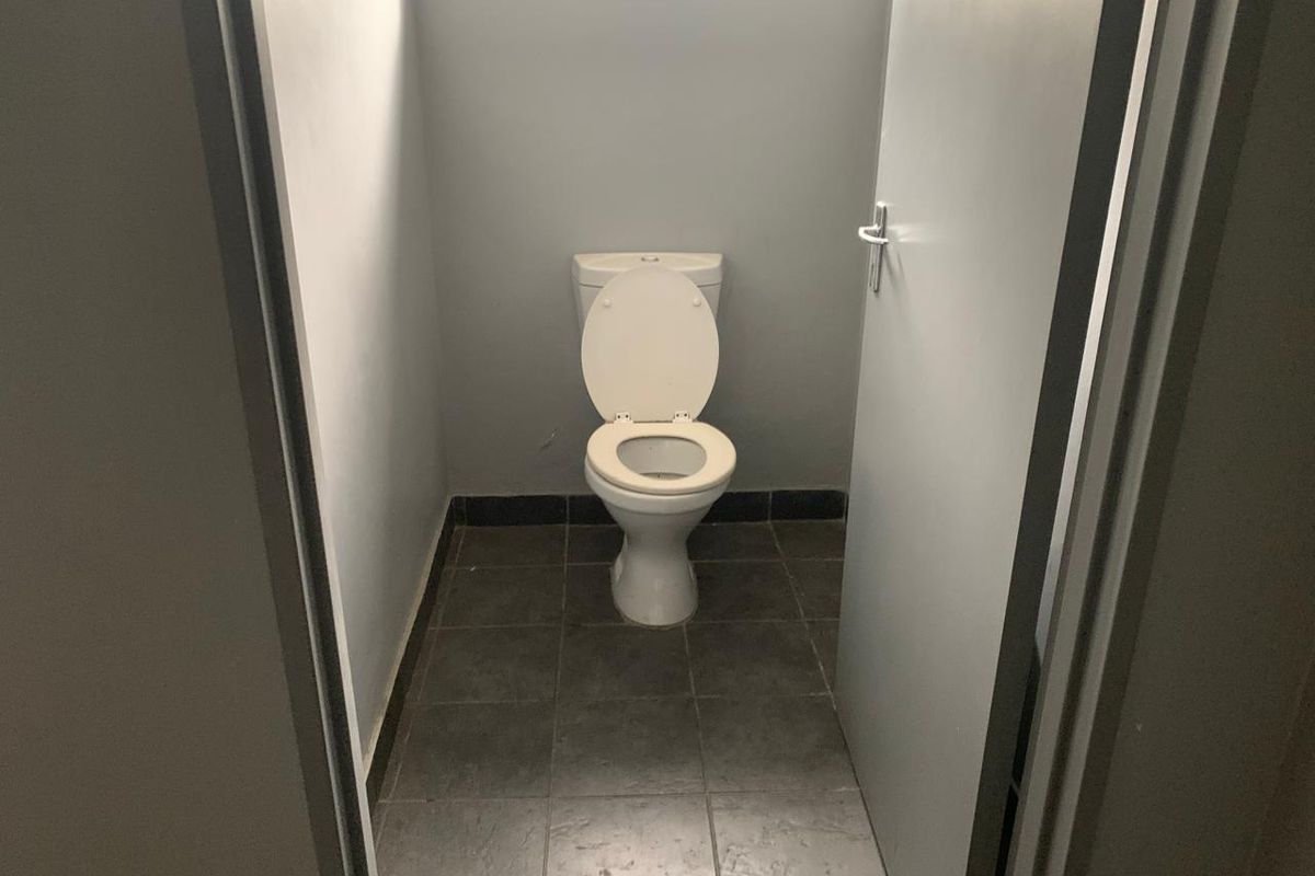 A functional industrial restroom featuring tiled flooring and a standard toilet fixture.