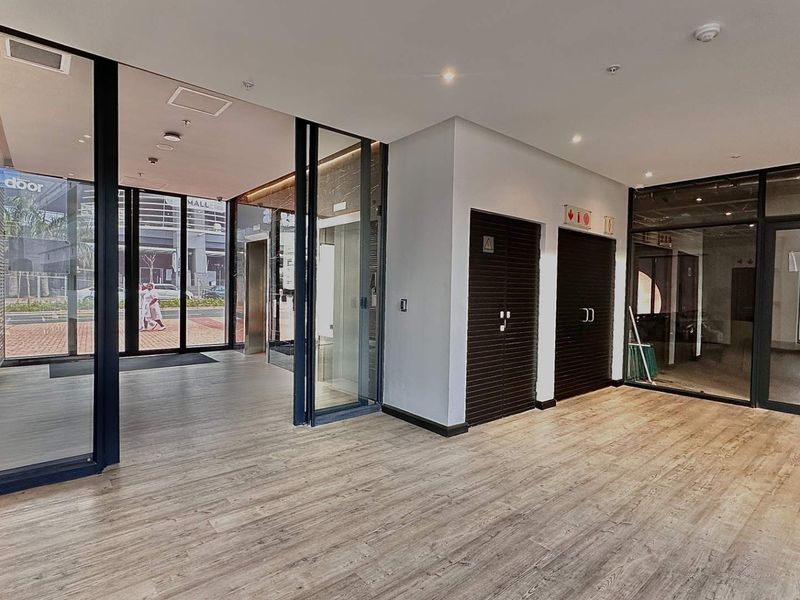 Modern office lobby or reception area featuring wood-look flooring, glass partitions, and secure access doors in a professional commercial building setting.