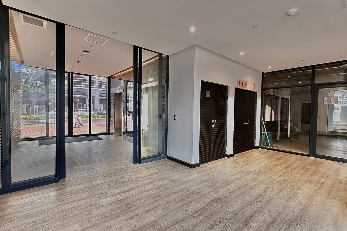 Modern office lobby or reception area featuring wood-look flooring, glass partitions, and secure access doors in a professional commercial building setting.