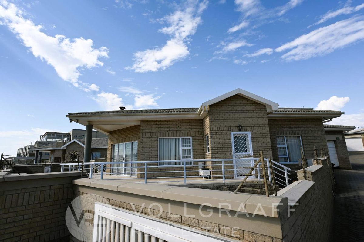 Exterior view of a townhouse featuring a brick facade, a raised patio area with metal railings, and tiled roofing.