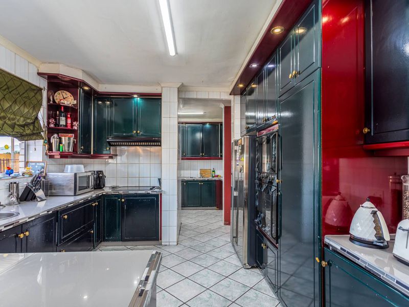 Spacious kitchen featuring dark cabinetry, tiled flooring, and a double wall oven, with an adjoining scullery area for additional prep and storage space.