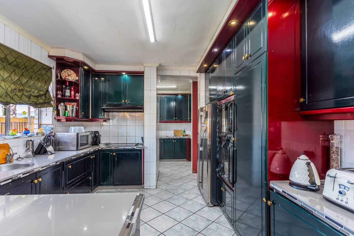 Spacious kitchen featuring dark cabinetry, tiled flooring, and a double wall oven, with an adjoining scullery area for additional prep and storage space.