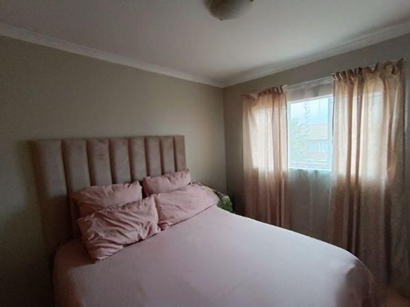 A cozy bedroom featuring neutral wall tones, a flush mount ceiling light, and a window with curtains, providing a comfortable and functional sleeping space.