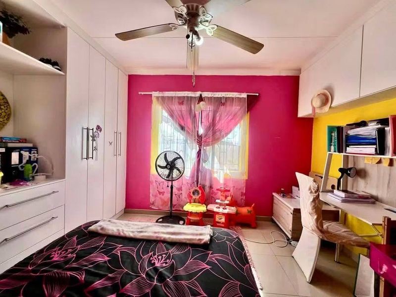 A bedroom featuring built-in cupboards, overhead storage cabinets, a ceiling fan, and tiled flooring, offering practical storage and functional living space.