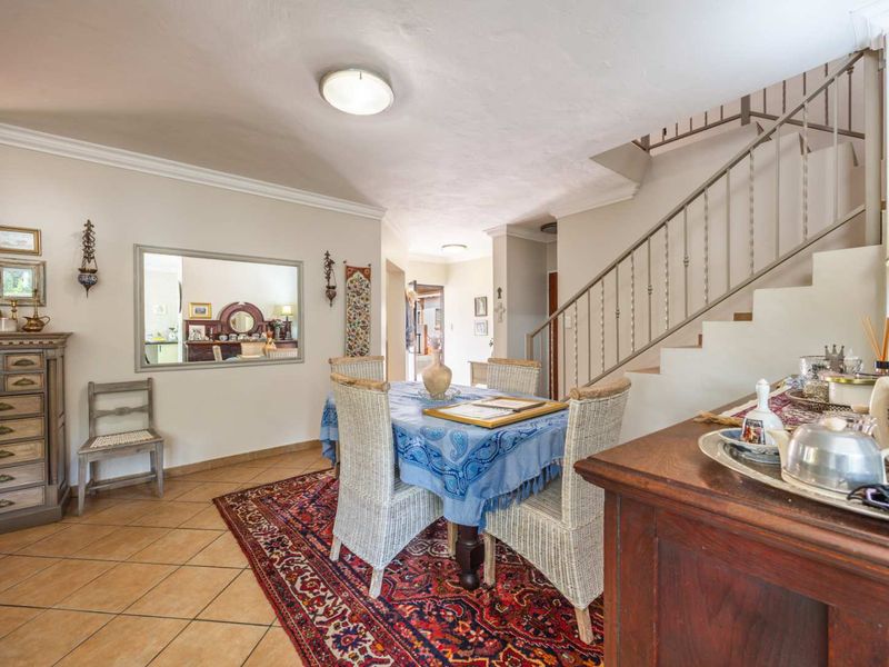 Dining area featuring tiled flooring, coved cornicing, and an open staircase with a metal balustrade, providing a functional and connected living space.