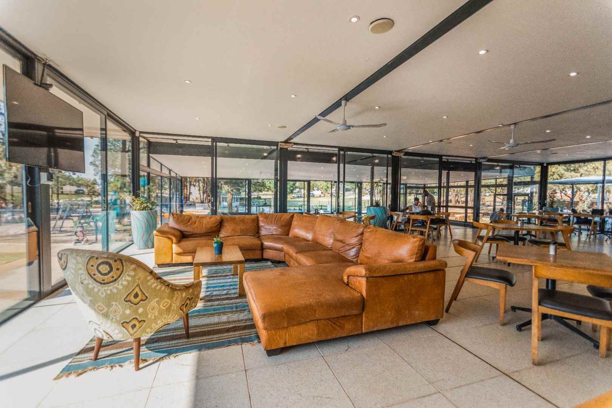 Spacious open-plan living area featuring extensive floor-to-ceiling glass walls, recessed lighting, ceiling fans, and neutral tiled flooring.