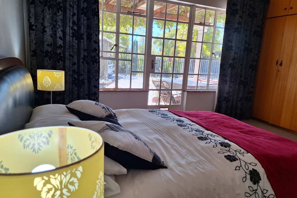 A bedroom featuring built-in wooden cupboards and large glass-paned doors that open directly onto an outdoor patio area.