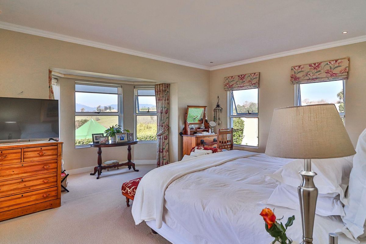 Spacious bedroom featuring large bay windows with scenic views, neutral carpeting, recessed lighting, and crown molding.