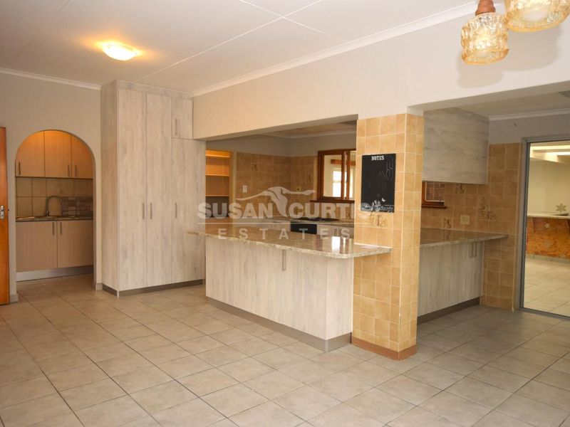 Spacious open-plan kitchen area featuring tiled flooring, granite countertops, and ample built-in cabinetry with a separate pantry access.