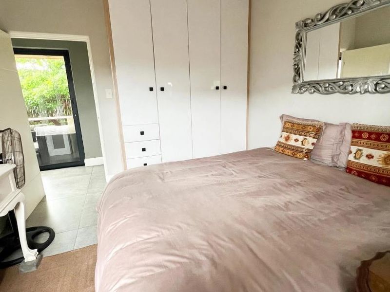 A well-maintained bedroom featuring built-in cupboards, recessed lighting, and a sliding glass door providing access to an outdoor area.