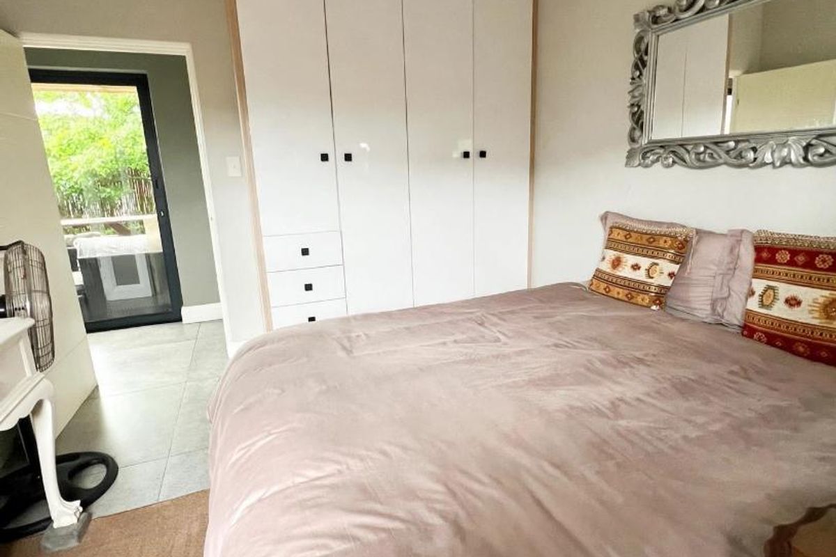 A well-maintained bedroom featuring built-in cupboards, recessed lighting, and a sliding glass door providing access to an outdoor area.