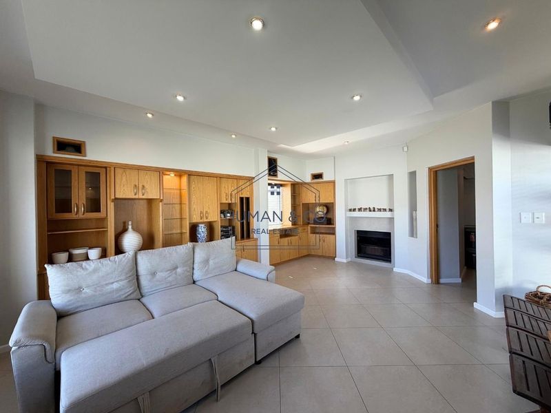 Spacious living room featuring built-in wooden cabinetry, a fireplace, recessed lighting, and neutral tiled flooring.