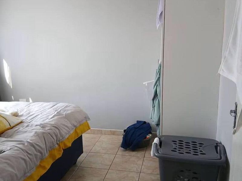 A functional bedroom featuring tiled flooring and a built-in cupboard, offering a neutral base for personalization.