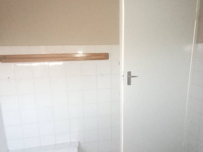 A basic bathroom featuring a bathtub, white wall tiling, and tiled flooring, currently in need of cosmetic updates.