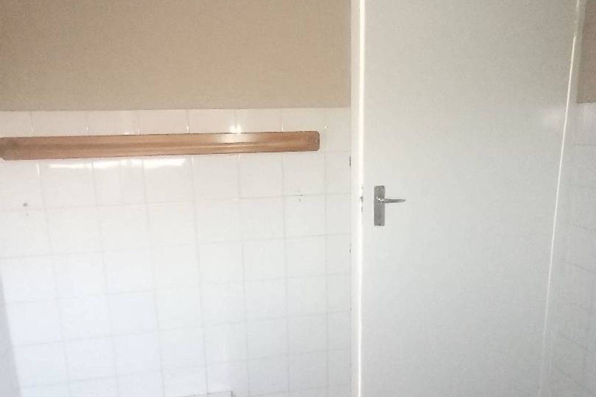 A basic bathroom featuring a bathtub, white wall tiling, and tiled flooring, currently in need of cosmetic updates.