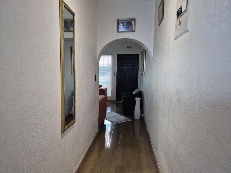 A functional hallway featuring an arched entryway, laminate flooring, and a wall-mounted electrical distribution board.