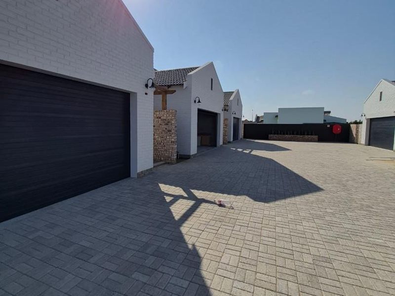 A well-maintained townhouse complex exterior featuring paved driveway access and multiple garage units with modern brick finishes.