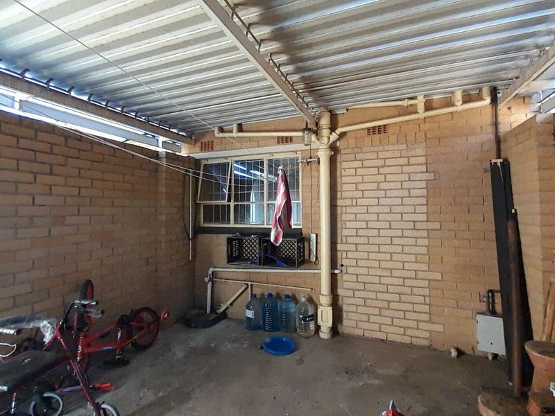 A covered outdoor patio area featuring exposed brick walls, a corrugated metal roof, and functional plumbing infrastructure.