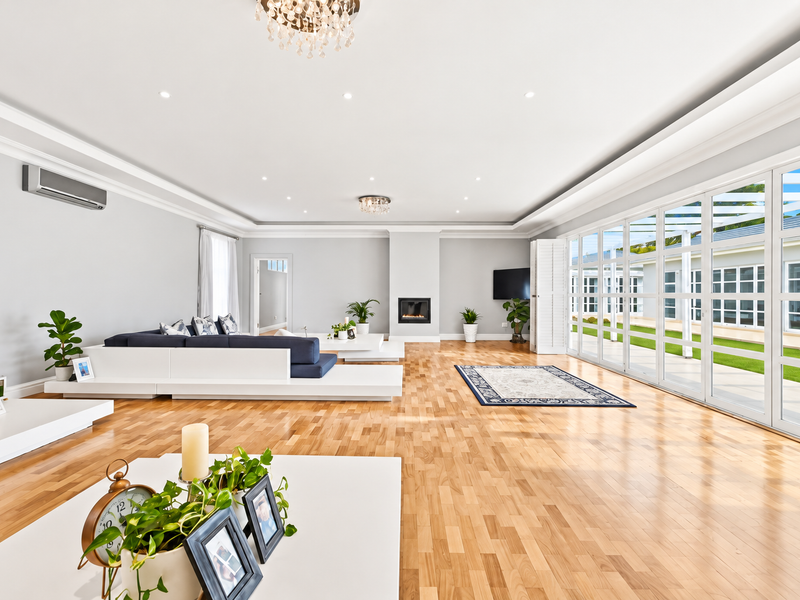Spacious living room featuring hardwood floors, recessed lighting, a built-in fireplace, and large glass doors opening to an outdoor patio area.