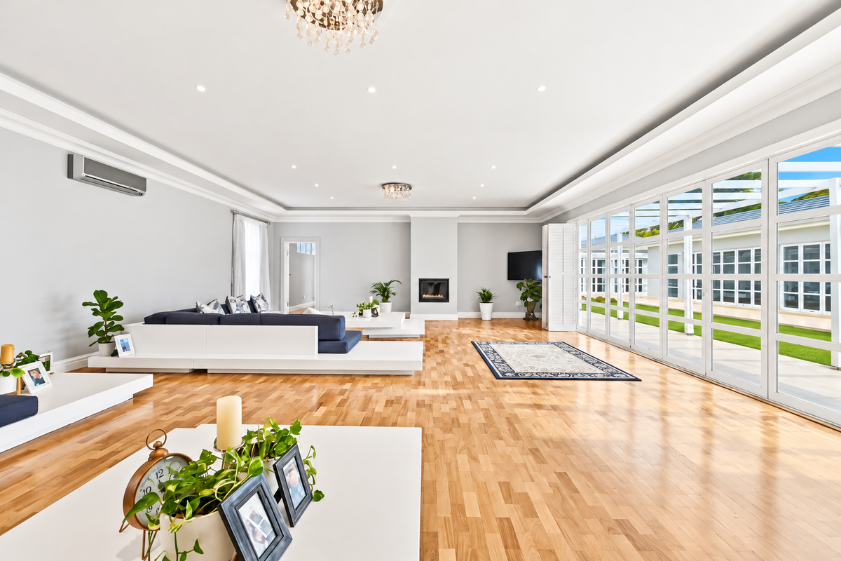 Spacious living room featuring hardwood floors, recessed lighting, a built-in fireplace, and large glass doors opening to an outdoor patio area.