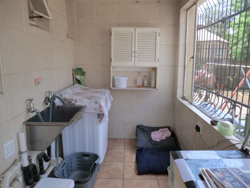 A functional laundry area featuring a stainless steel utility sink, wall-mounted cabinetry, and tiled finishes, providing a practical space for household chores.