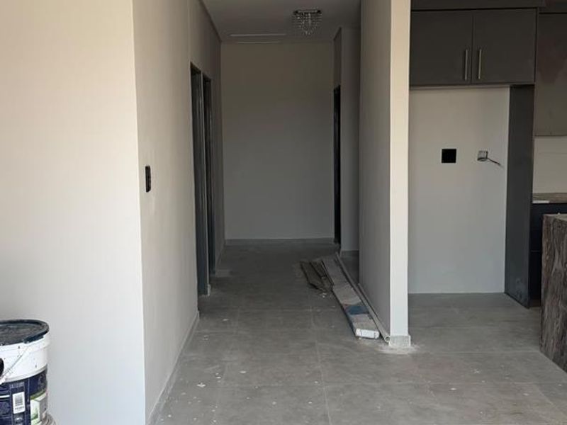 An open-plan living area under construction, featuring modern recessed ceiling details, neutral wall finishes, and large format floor tiles.