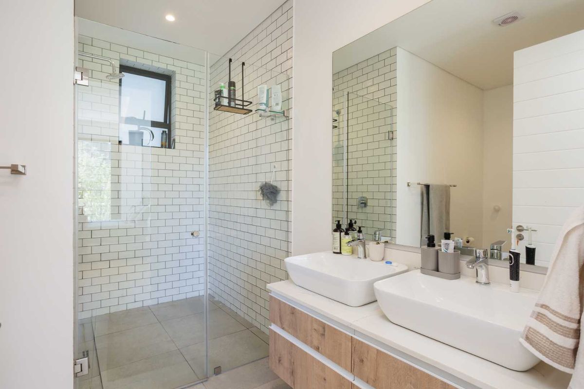 Modern bathroom featuring a double vanity with vessel sinks, a large wall-mounted mirror, and a walk-in shower with subway tile surround.