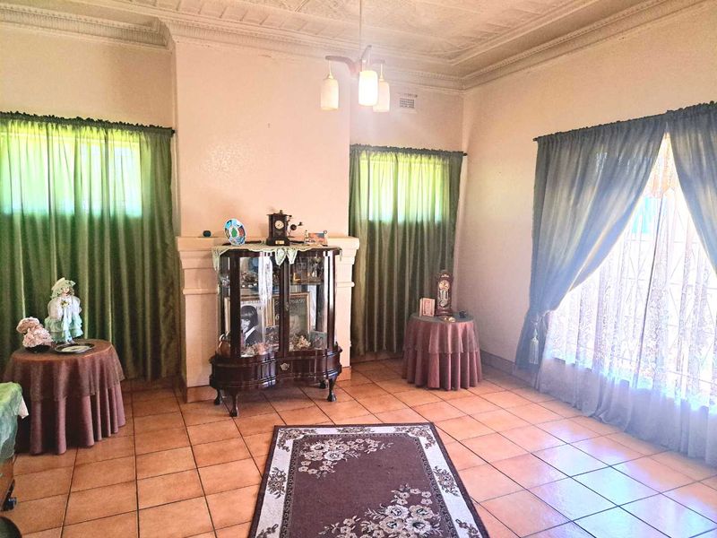 Spacious living room featuring classic pressed metal ceilings, ceramic tiled flooring, and a central fireplace surround, offering a traditional aesthetic.