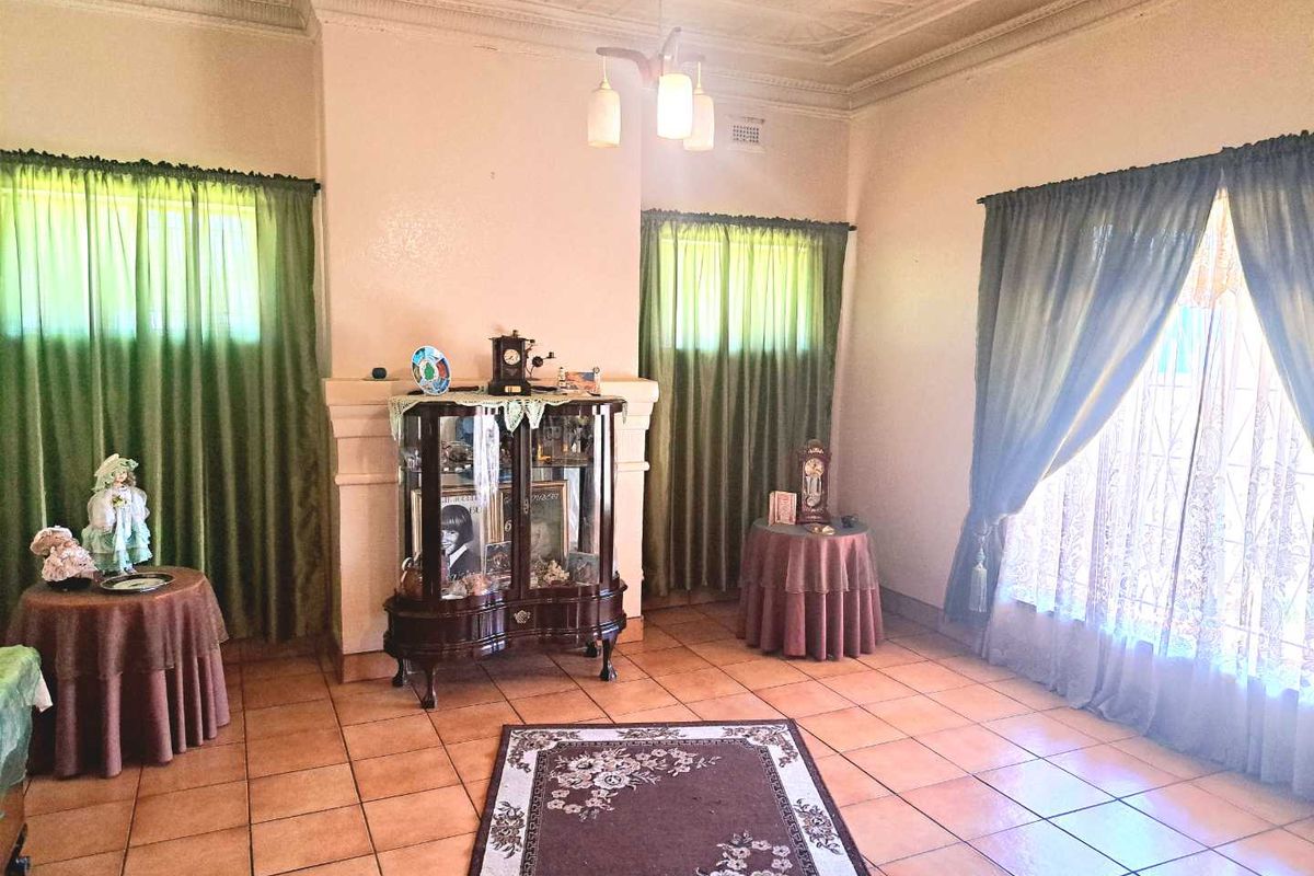 Spacious living room featuring classic pressed metal ceilings, ceramic tiled flooring, and a central fireplace surround, offering a traditional aesthetic.
