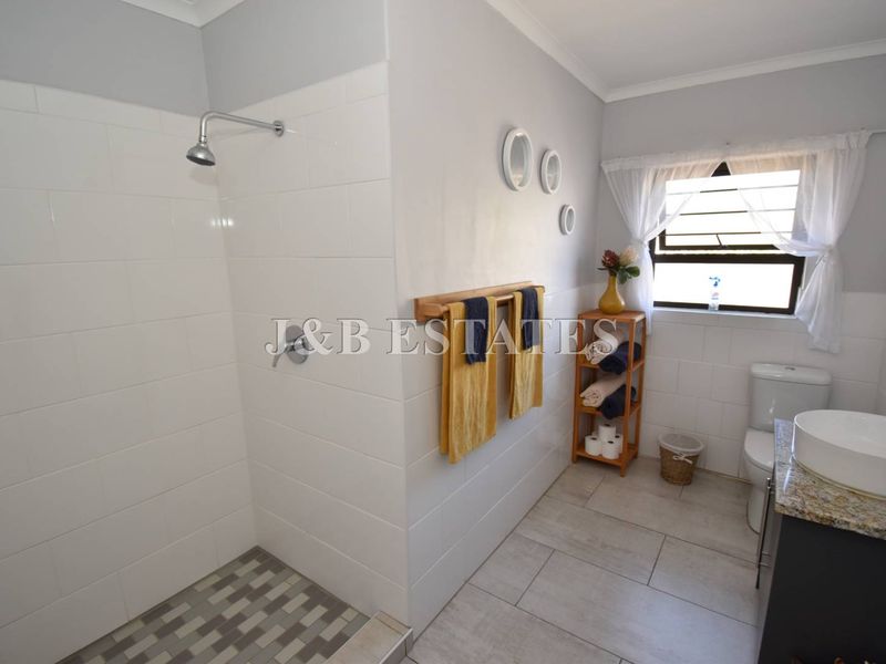 A clean, modern bathroom featuring a walk-in shower with tiled walls, a vanity with a vessel sink, and a toilet.