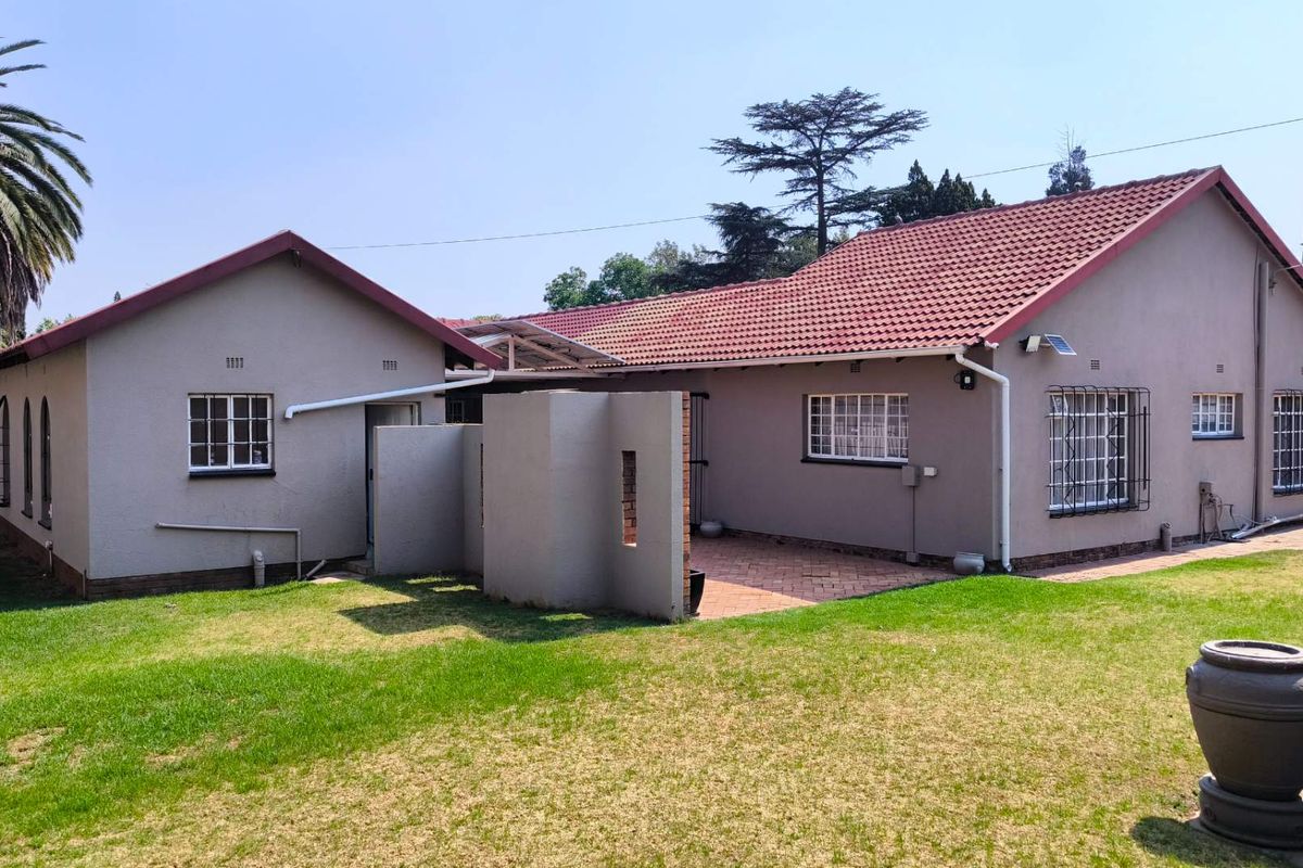 Rear view of the house featuring a paved patio area, well-maintained lawn, and tiled roof structure.