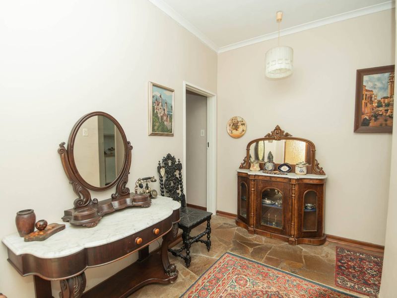 A spacious hallway featuring natural stone flooring, neutral wall finishes, and classic cove cornicing, providing a warm and welcoming transition between living areas.