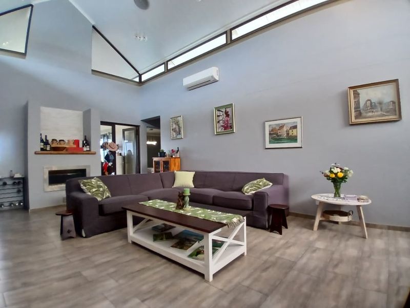 Spacious living room featuring a high vaulted ceiling with clerestory windows, modern laminate flooring, and a built-in fireplace.