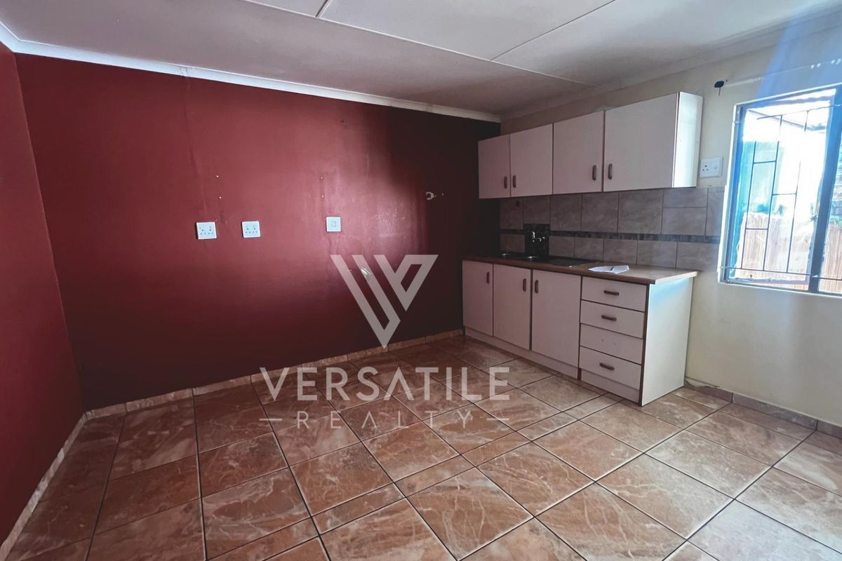 A functional kitchen area featuring tiled flooring, built-in cabinetry, and a tiled backsplash, providing a practical space for culinary activities.