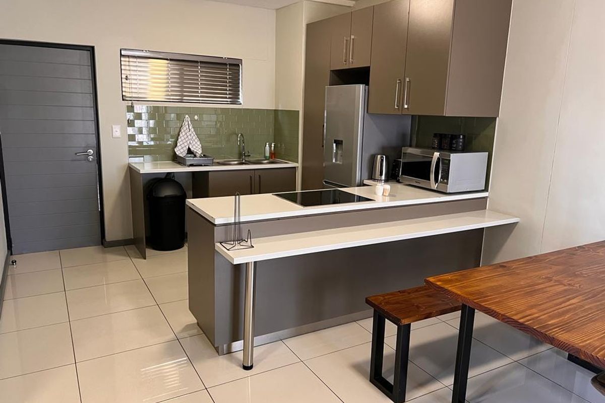 Modern kitchen featuring sleek cabinetry, stone countertops, a subway tile backsplash, and integrated hob, set against polished ceramic tile flooring.