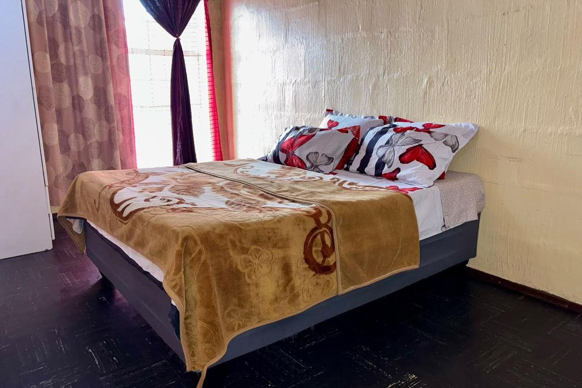 A bedroom featuring dark flooring and textured walls, offering a functional space that could benefit from modern updates and refreshed finishes.