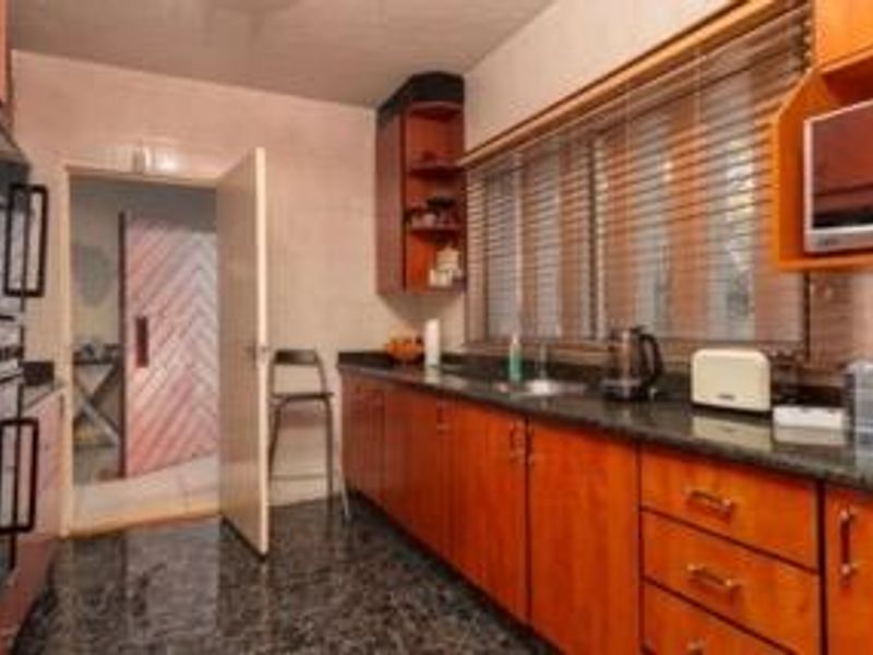 A functional kitchen featuring wood-toned cabinetry, granite countertops, and a built-in double oven, offering a classic layout with potential for modern updates.