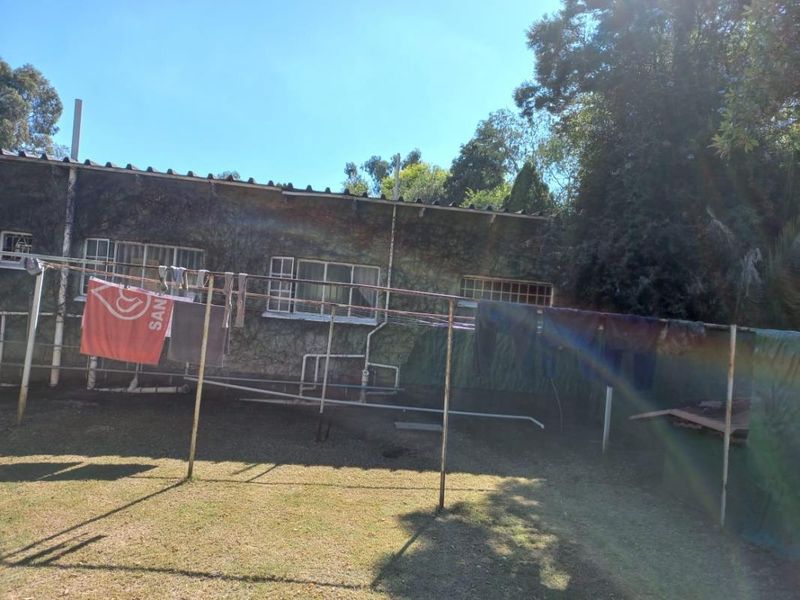 Rear exterior view of the property showing the building facade with visible organic growth and external plumbing infrastructure.