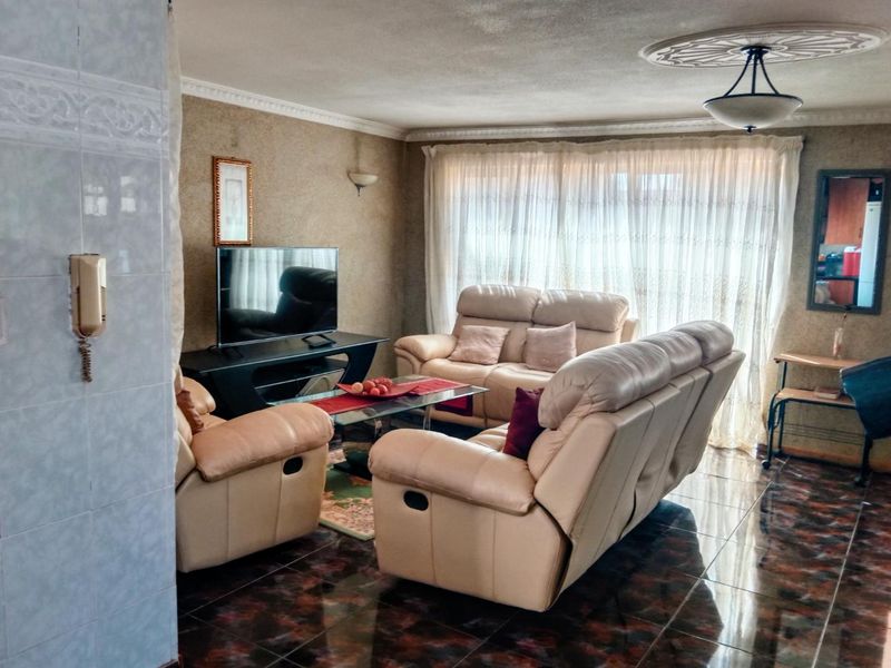 A living room featuring tiled flooring, decorative ceiling rose, and coving, providing a functional space with an integrated intercom system.