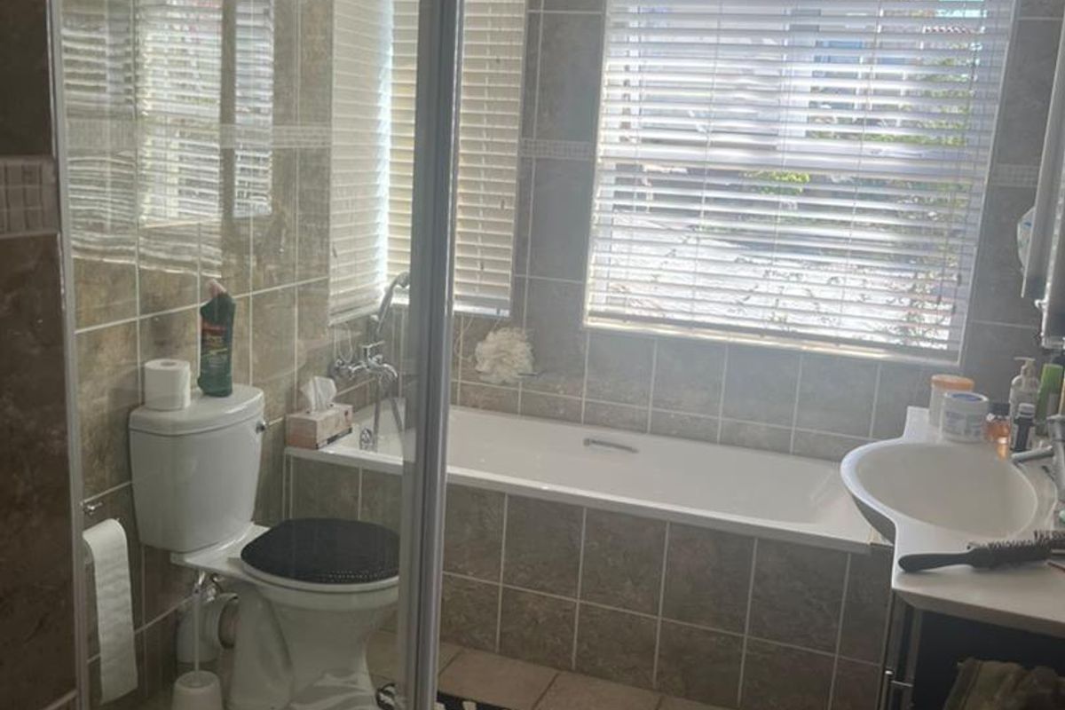 A functional bathroom featuring a tiled shower enclosure, a built-in bathtub, a toilet, and a vanity basin with tiled walls and flooring.