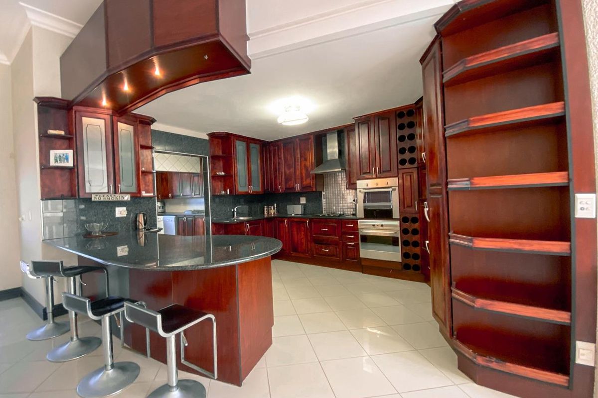 Spacious kitchen featuring dark wood cabinetry, granite countertops, a breakfast bar, built-in oven, and integrated wine rack storage.