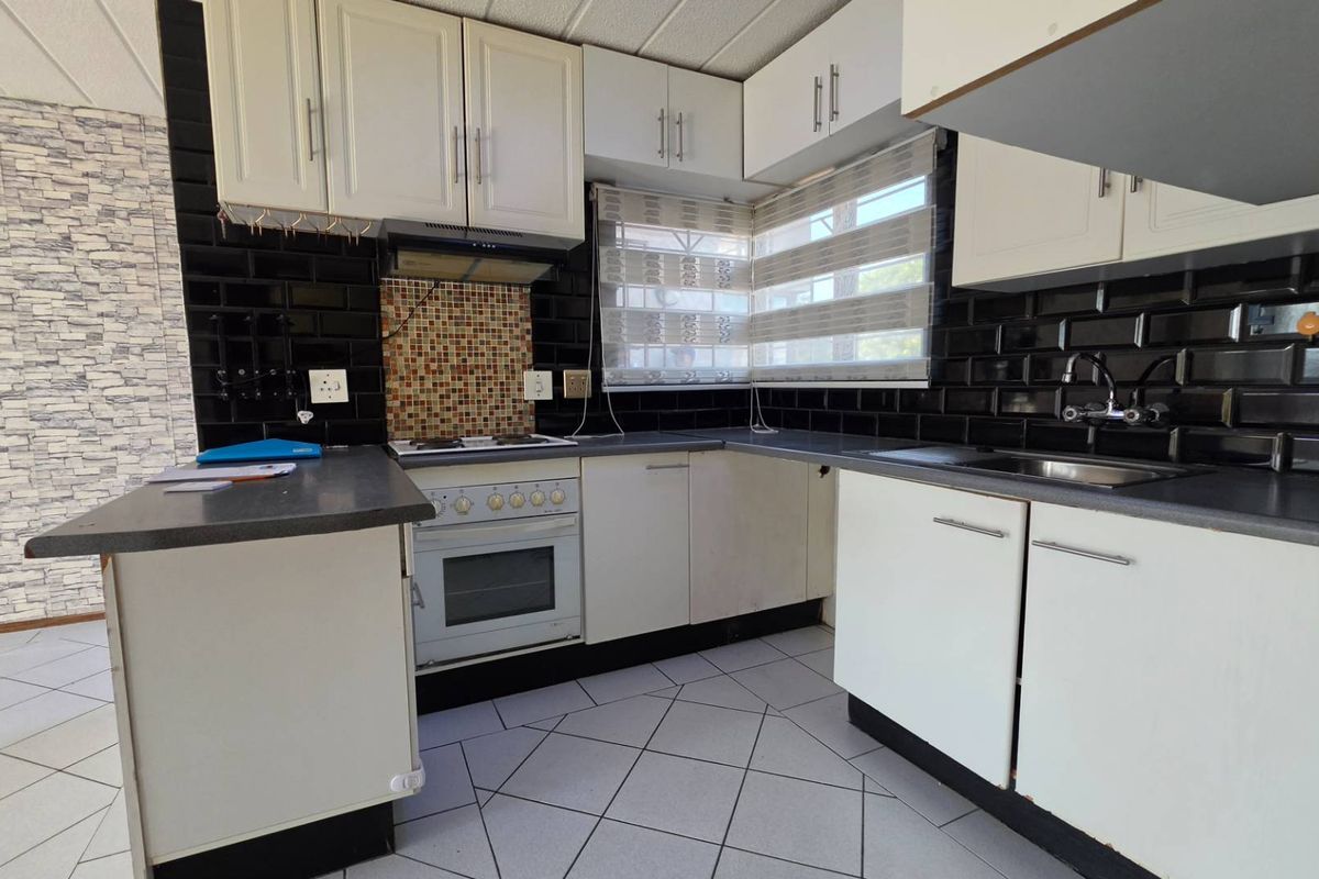 A functional kitchen featuring white cabinetry, black subway tile backsplash, built-in oven with hob, and tiled flooring.