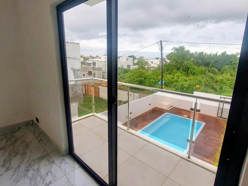Interior view looking out through large sliding glass doors onto a private balcony featuring a swimming pool and glass balustrade.