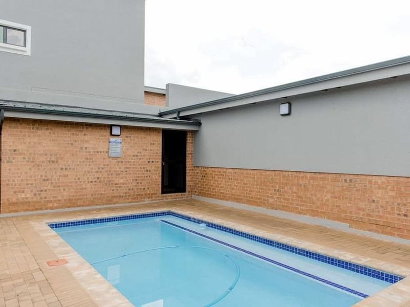 A private swimming pool area featuring paved surrounds, brick boundary walls, and integrated pool infrastructure.