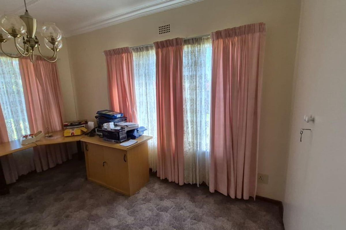 A bedroom featuring large windows with curtains, carpeted flooring, and a built-in cupboard.