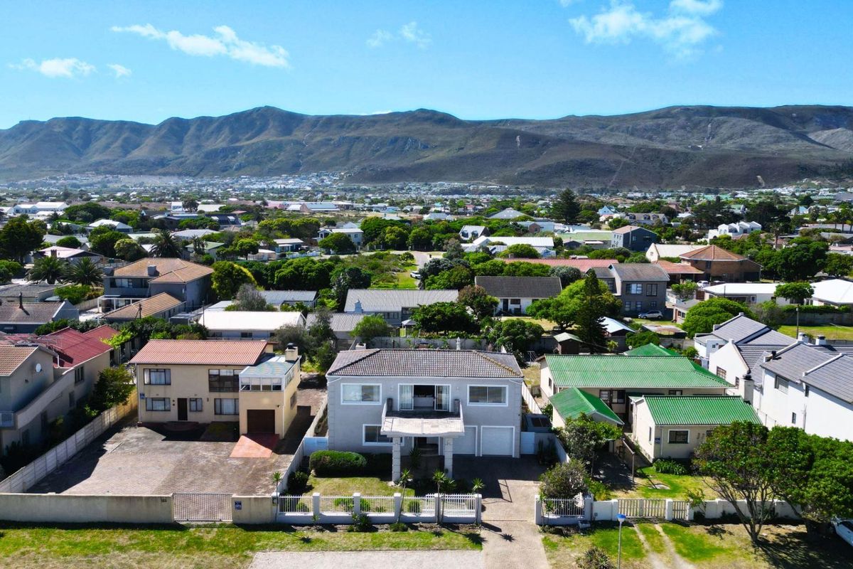 Aerial view of the property showing the front facade, driveway, and surrounding residential neighbourhood with mountain views in the background.
